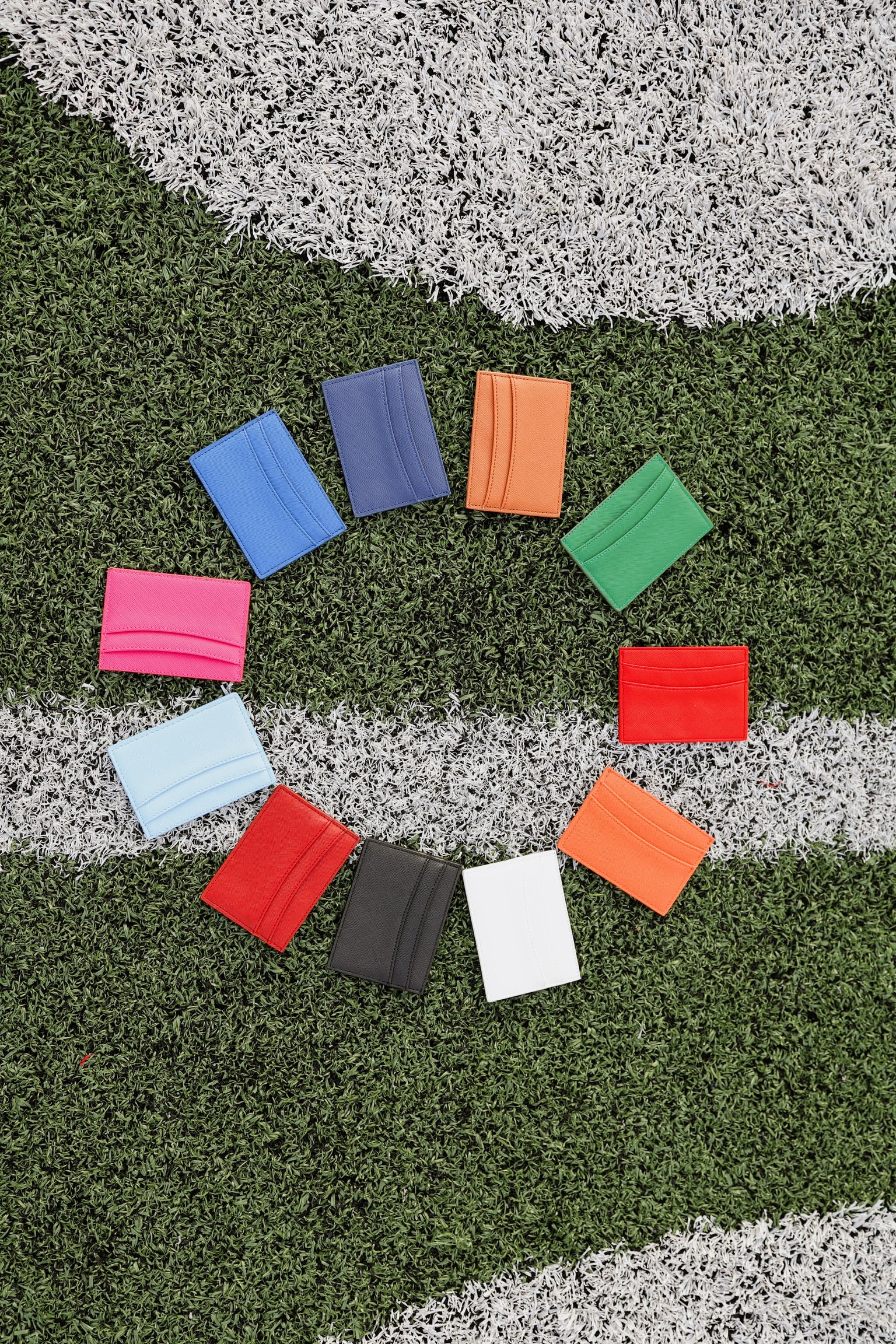 Colorful card wallets arranged in a circle on a grass football field