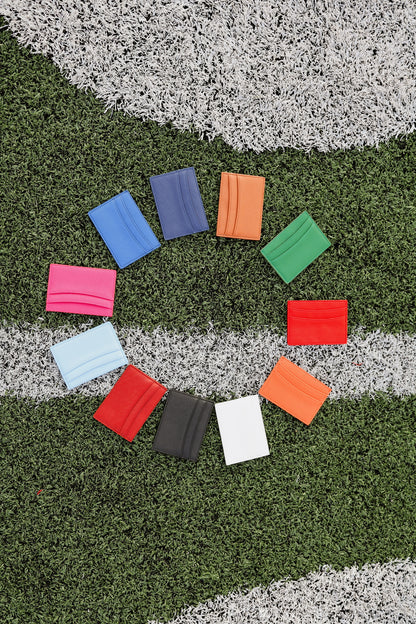 Colorful card wallets arranged in a circle on a grass football field