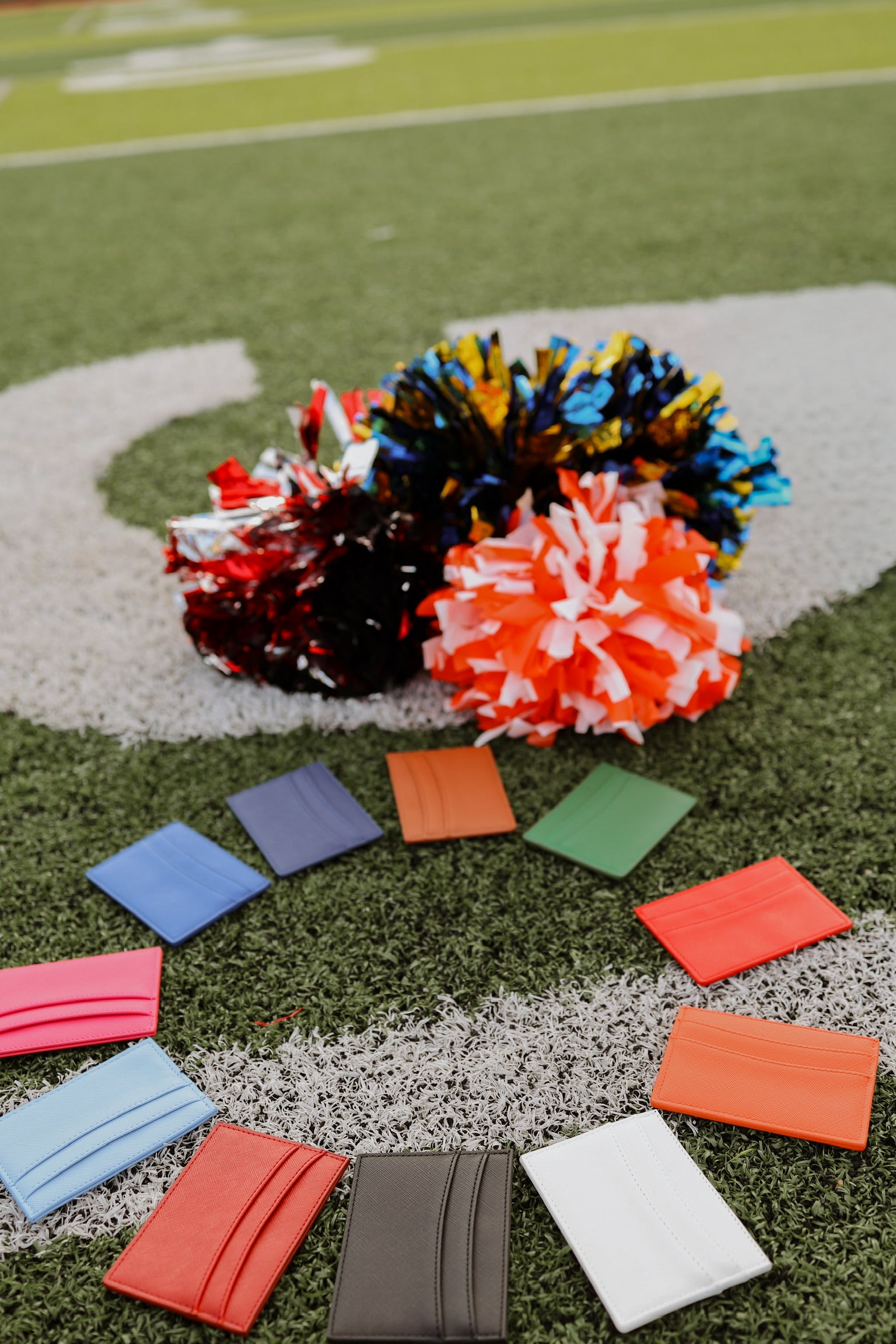 Colorful pom-poms and scard holder wallets on a sports field