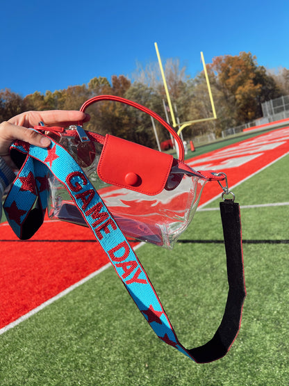 Clear bag with red handle and blue 'Game Day' beaded strap on a sports field.