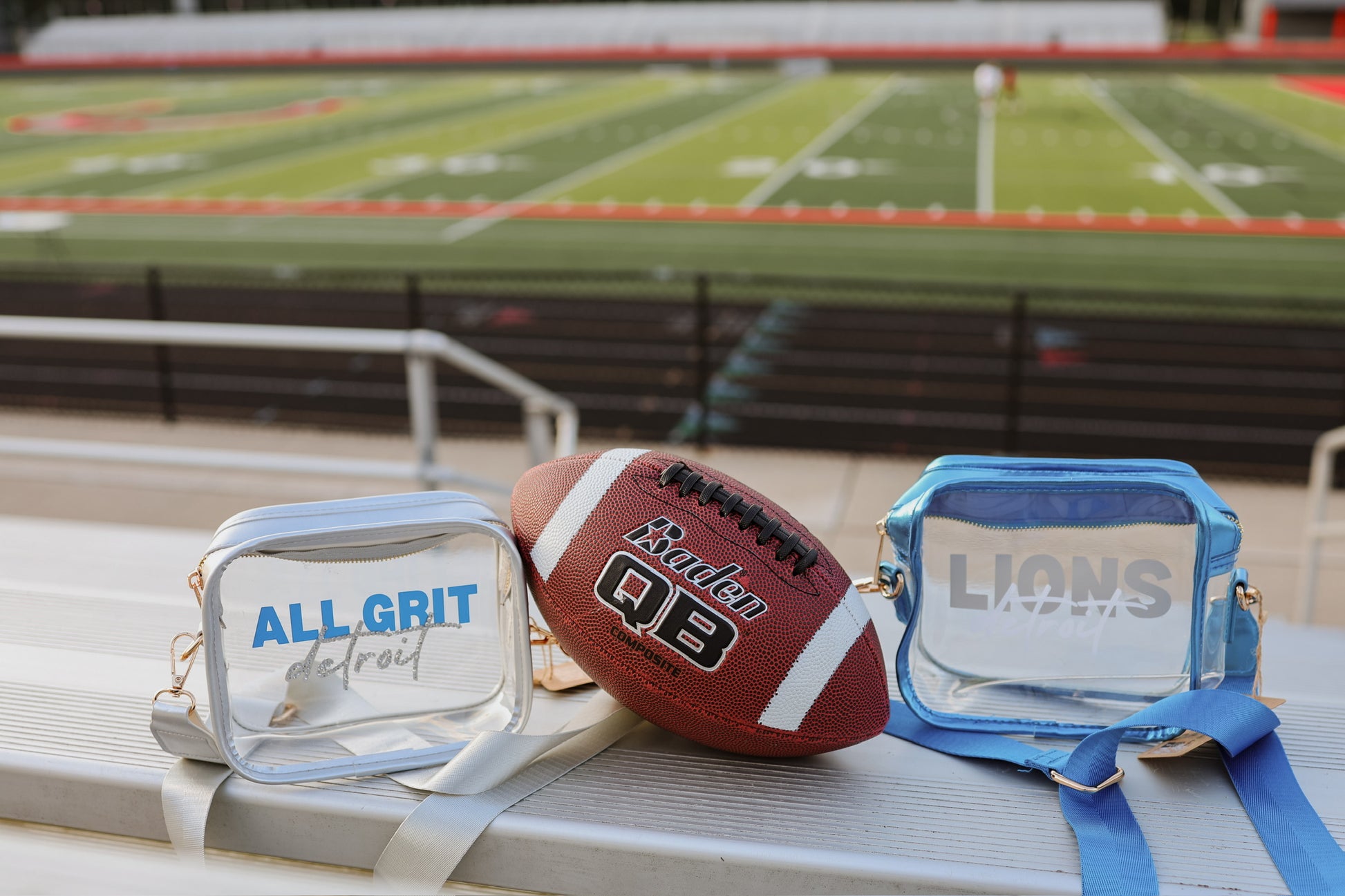 Football and clear stadium bags with 'All Grit' and 'Lions' text on a sports field background