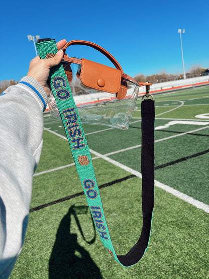 Handbag with a beaded green 'GO IRISH' strap held on a sports field.